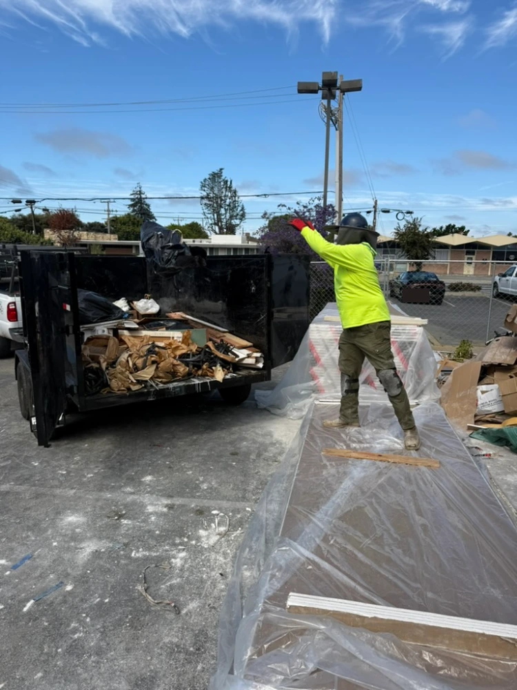 Crew member tossing debris into a loaded dump trailer